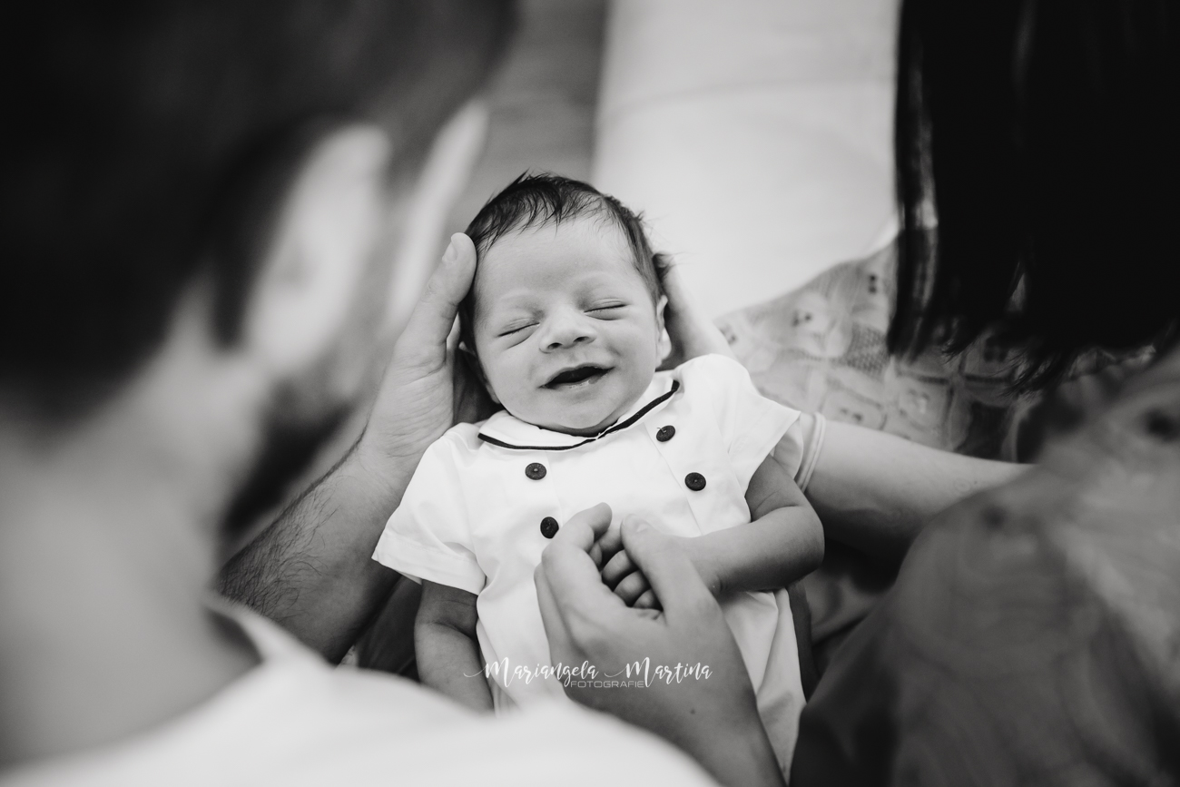 bambino neonato sorridente tra le braccia di mamma e papà