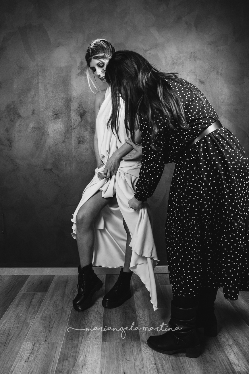 Collaborare è fondamentale per la buona riuscita di un progetto. Durante questo shooting sono state coinvolte diverse figure professionali, tutte diverse tra loro. In questa foto infatti la stilista Rossana Prisciantelli mentre sistema l'abito indossato dalla modella